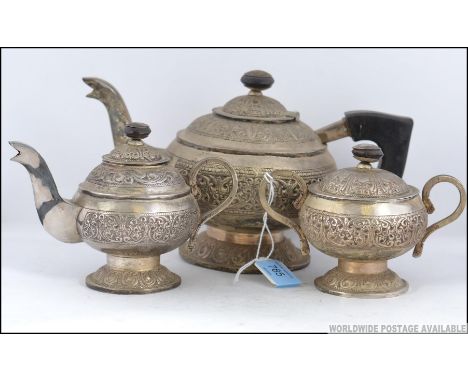 An anglo indian silver plated tea service cast in relief having scrolling design comprising teapot, sugar bowl and creamer. M