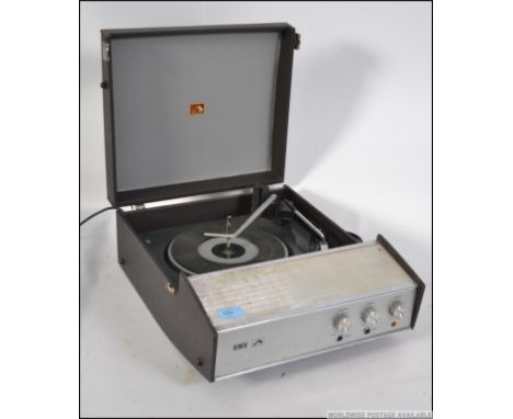 A vintage mid 20th century four speed portable record player by HMV, having a lift up lid and carry handle to the side.