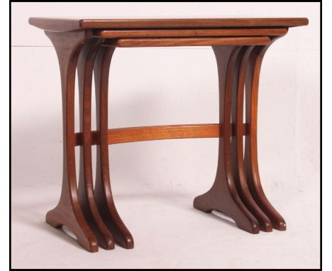 A 1970's teak wood nest of table raised on splayed legs with bow stretchers having graduated tops to each