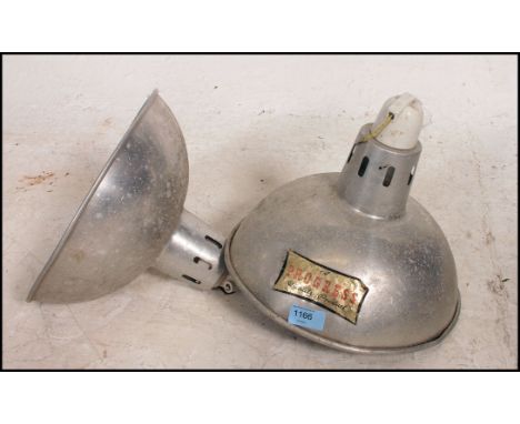 A pair of retro industrial chrome pendant light fixtures bearing applied makers label for Progress