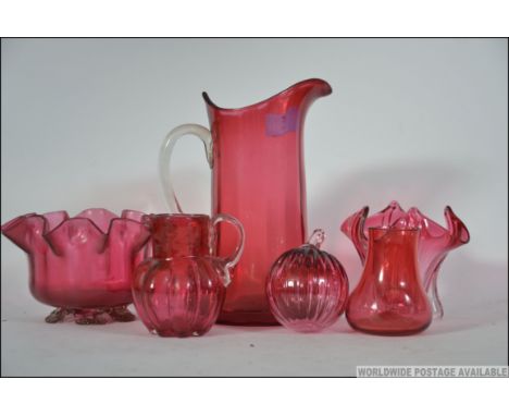 A collection of cranberry glass wares to include a Christmas ball ball, pitcher, jug, bowls etc. Measures: 19cms high.