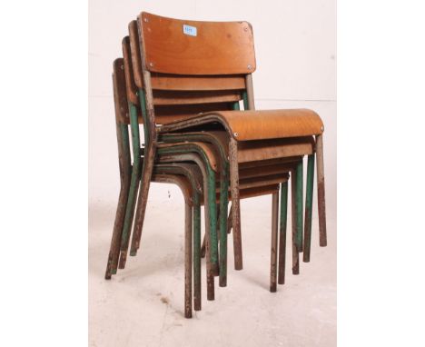 A stack of 6 mid century childrens school stacking chairs having panel seats and back rests being raised on tubular supports