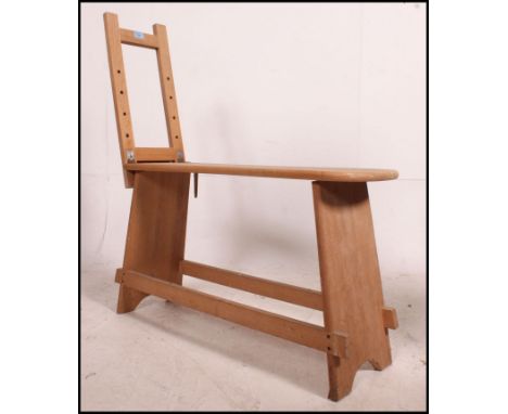 A mid century Artists bench with shaped seat on lyre supports, one end raising into an easel