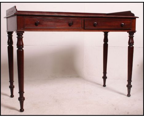 A Victorian mahogany writing table desk being raised on turned legs having twin fitted frieze drawers with the desk top havin