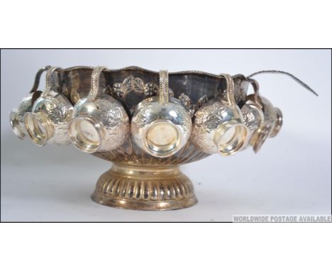 A decorative 20th century silver plated punch bowl, complete with all cups and matching ladle. Each heavily embossed with nat