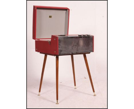 A vintage 1950's HMV ( His Masters Voice ) red portable record player raised on a wooden plinth with tapering dansette lets