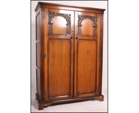 A Jacobean revival double wardrobe with geometric carved panel work base raised on a plinth base dating to the 20th century. 