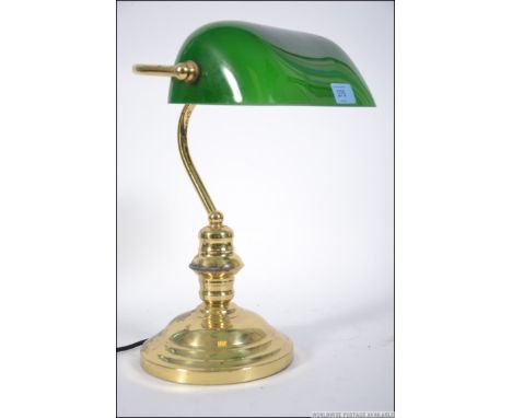 A 20th century bankers desk lamp having a green glass shade raise on a brass support. Measures: 33cms high.