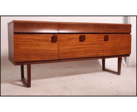 A 1970's retro teak wood sideboard raised on angled legs united by stretchers with inverted bow front short drawers over cupb