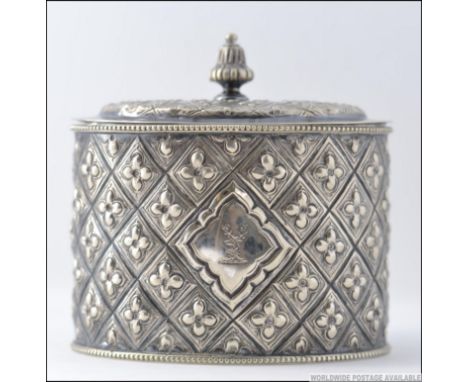 An early 20th century silver plated tea caddy of oval barrel form being cast in relief with hinged top and finial centre. Mea