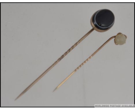 A 9ct gold and agate stone set stick pin, the large stone of oval form, weight 4.5g. Together with another yellow metal stick