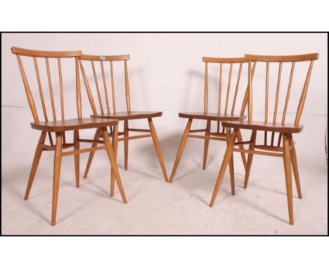 A set of 4 1970's Ercol beech and elm dining chairs being raised on turned legs united by stretchers having panel seats with 