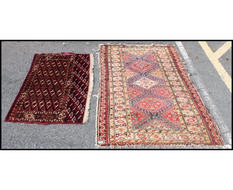 A Persian / Iranian floor rug, red ground, having floral borders with geometric central panel, along with another rug. Measur