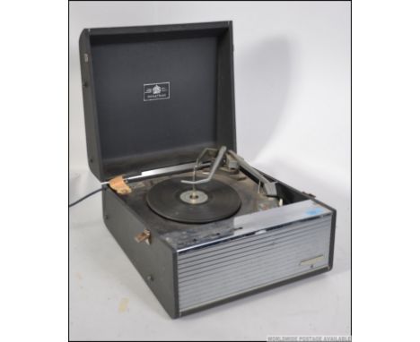 A retro 20th century four speed portable record player by Dynatron, having a lift up lid and carry handle to the side.