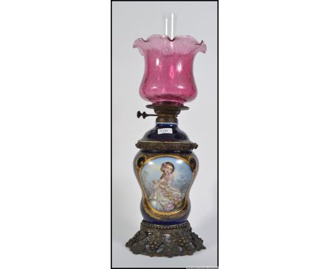 A Victorian Wright & Butler brass, ceramic and cranberry glass shade oil lamp complete with the flue. The brass grape and vin