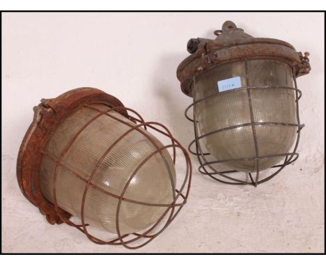 A pair of Industrial mid century factory bulkhead pendant lights. Each with cage surround, thick glass bulbs with original br