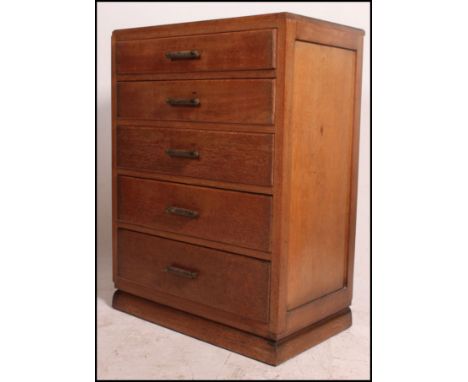 A 1930's Art Deco oak chest of drawers being raised on a shaped plinth with an upright bank of drawers each with bar handles.