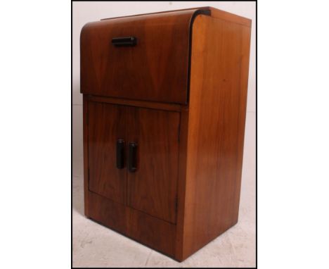 A 1930's Art Deco bow front walnut cocktail drinks cabinet having hinged top with appointed interior over cupboard beneath. M