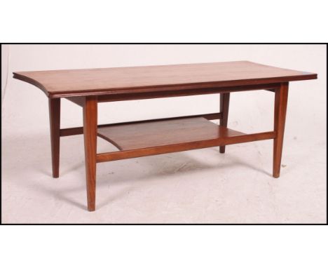 A 1970's retro teak wood Danish style coffee table being raised on tapered supports with inverse bow ends to the rectangular 