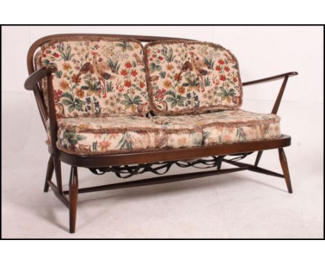 An Ercol beech and elm Windsor pattern 2 seat sofa settee complete with the cushions. Matching armchairs in lot 1024