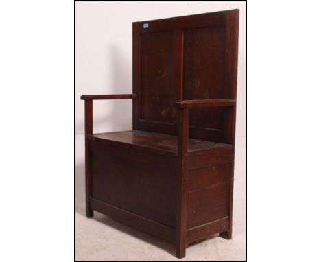 A 1930's oak hall settle with box seat having hinged top being flanked by shaped elbow supports and panel back rest. Measures