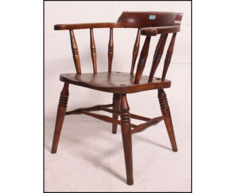 A 19th / 20th century beech and elm smokers bow captains armchair being raised on double 'H' stretcher base to the turned leg