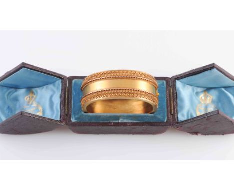 A YELLOW PRECIOUS METAL BANGLE, circa 1870, the symmetrical mount of subtle applied metal scroll work and beaded detailing se