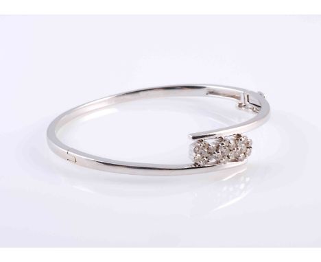A DIAMOND SET BANGLE, the three clusters of slightly graduating brilliant cut claw set diamonds each set into three flower he