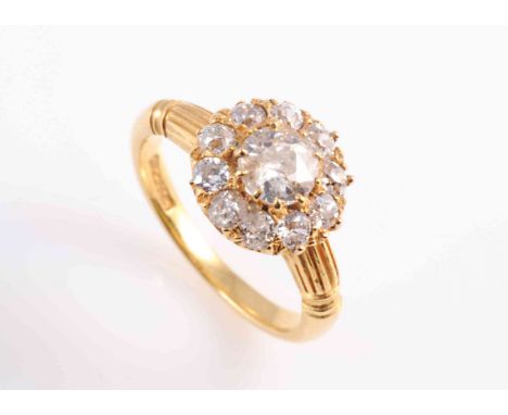 A DIAMOND RING, CIRCA 1880, the old brilliant cut diamond ten claw set raised within a surround of ten old brilliant cut and 