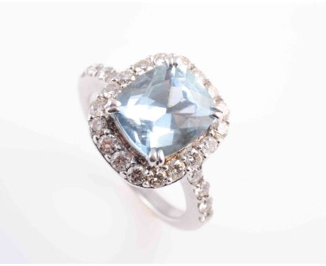AN AQUAMARINE AND DIAMOND RING, the square cushion cut aquamarine four double claw set raised within a surround of eighteen b