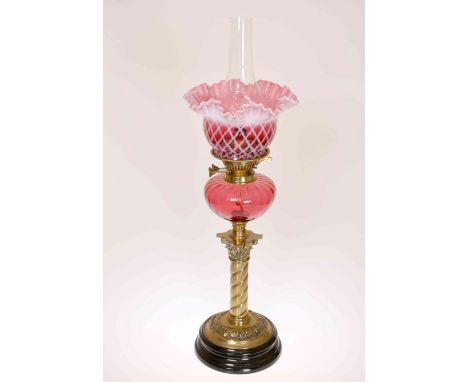 A VICTORIAN BRASS AND CRANBERRY GLASS OIL LAMP, with ropetwist column and Corinthian capital below a cranberry reservoir with