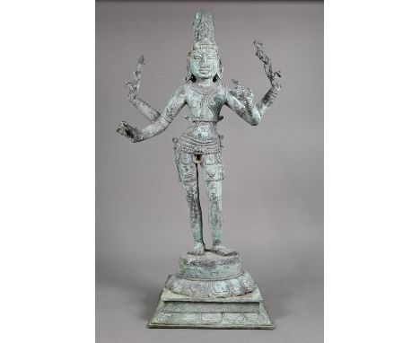 A large Indian bronze figure of the Hindu deity Shiva standing on a stepped lotus base in the Chola period style, aged applie