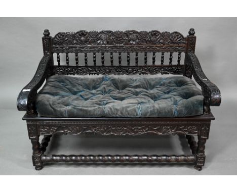 A profusely carved and moulded colonial ebonised hardwood sofa bench, with cane panelled seat (with associated buttoned velve