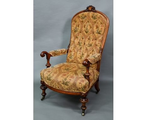 A Victorian walnut framed open armchair with carved crest, deep buttoned back and stuff-over seats, padded scroll arms, on tu