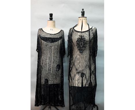 Two 1920s black 'flapper' dresses, heavily beaded and embellished on fine net, one with beaded cord sash (2) 