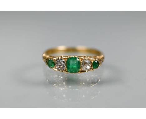 A five stone graduated emerald and diamond ring, 18ct yellow gold set, size M, the central rectangular emerald showing small 