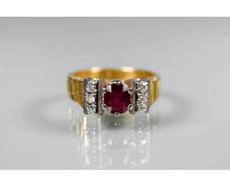 A 1970s style ring, the central oval ruby with three diamonds to each side, textured shank, yellow and white metal set stampe