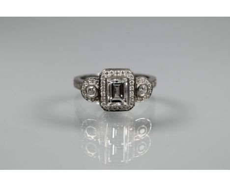 An Art Deco style diamond-set cluster ring, the central rectangular diamond flanked by a collet set diamond to each side, all