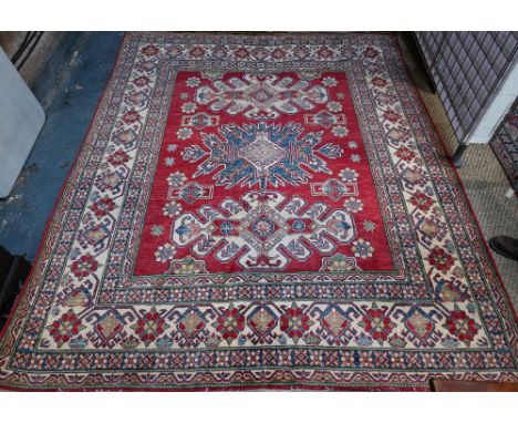 A contemporary Kazak carpet with pale red ground and stylized floral design within camel ground borders, 286 x 232 cm, simila