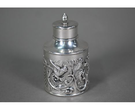 An Edwardian cylindrical silver tea caddy and cover, ornately embossed with exotic birds, snakes and foliage, Goldsmiths &amp