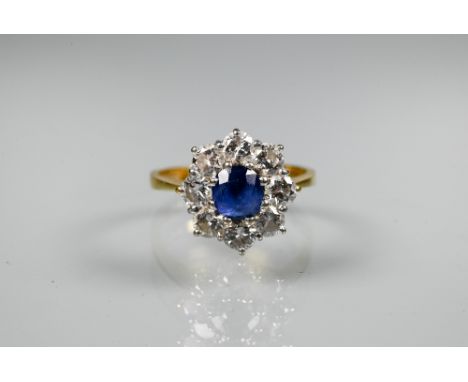 A sapphire and diamond cluster ring, the claw set blue sapphire surrounded by eight brilliant cut diamonds, 18ct yellow and w