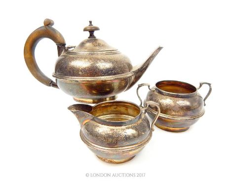 A sterling silver Bachelor's three piece tea set, Charles Boyton & Son Ltd, Birmingham 1922, the teapot having a fruitwood ha