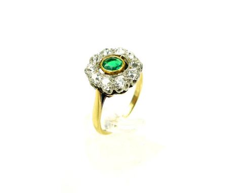 An exquisite, 18 ct yellow gold and platinum, emerald and diamond cluster ring, composed of a central, bezel set, round, face