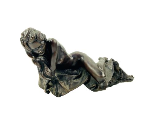 A patinated cast bronze sculpture of a female lying partially on her side on crumpled sheets, 39cms wide x 19cms deep x 16cms