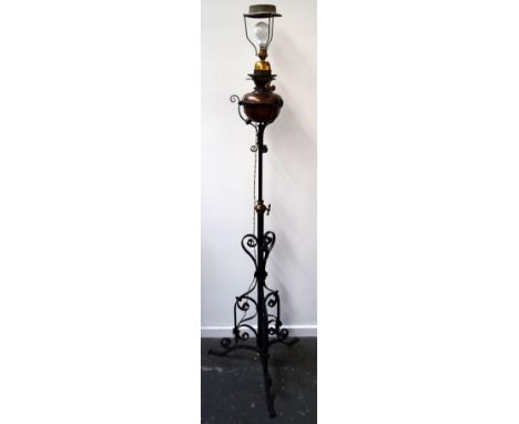 An interesting wrought iron adjustable standard lamp supporting an adapted duplex oil lamp with shade 175cm approx