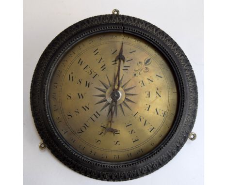 An early 20th century wall mounted compass/barometer  in decorative ebony frame with brass face 35cm Diameter