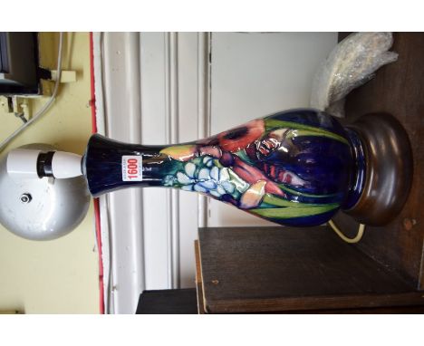 A Moorcroft vase form lamp, tubelined with orchids and other flowers against a blue ground, height excluding fitting 36cm.  