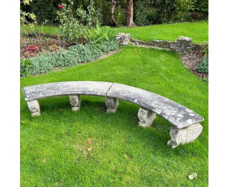 A reconstituted stone curved garden bench on five scroll supports, each marked "K" to base.240cm x 40cm 