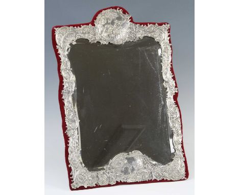 A late Victorian silver clad easel dressing table mirror, having a shaped rectangular mirrorplate within a foliate scrolling 