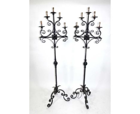 A pair of late Victorian wrought iron five-light freestanding candle stands, each black painted, later wired for electricity,